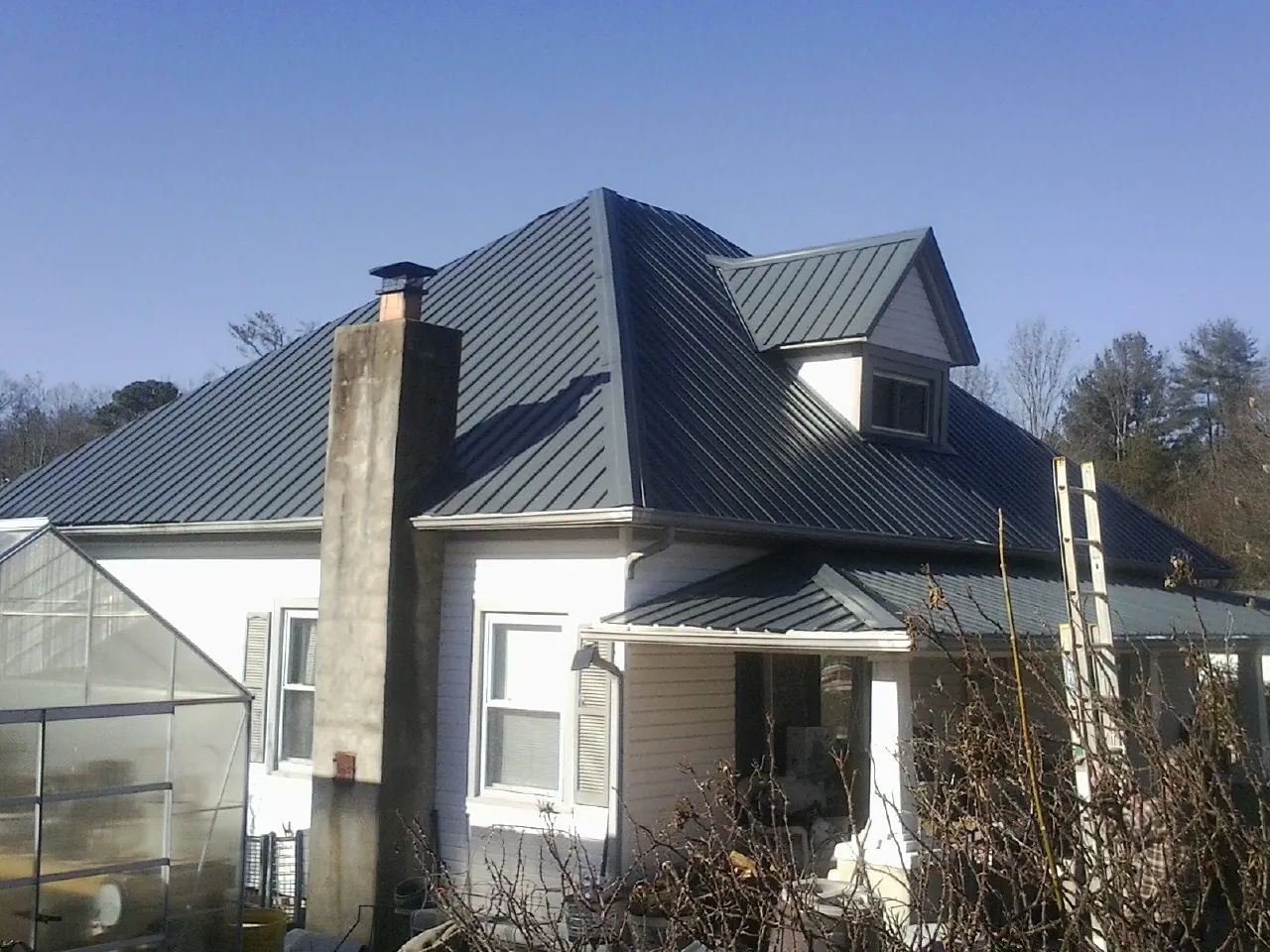 Dark blue standing seam metal roof on a white farmhouse with dormer — Slate & Tile Roof Repair by Roofing Brothers in Elizaville