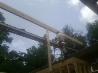 Carpenter setting a ridge beam over a new addition frame — Ice Dam Removal by Roofing Brothers in Elizaville