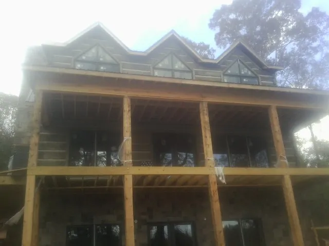 Dormers and porch framing on a large log home under construction — Roof Coating work by our crew in Elizaville