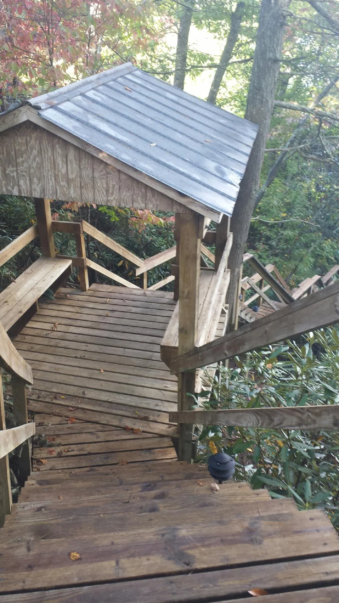 Metal roofed shelter over wooden steps on a wooded walkway — Skylight Repair & Installation work by our crew in Elizaville