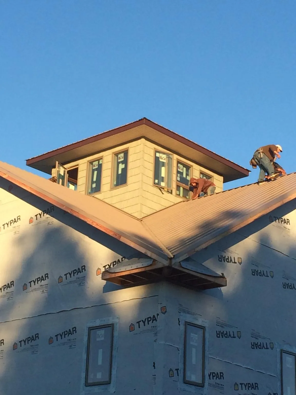 Roofers working around a rooftop cupola on a new metal roof at sunset — Roof Waterproofing in Elizaville by Roofing Brothers